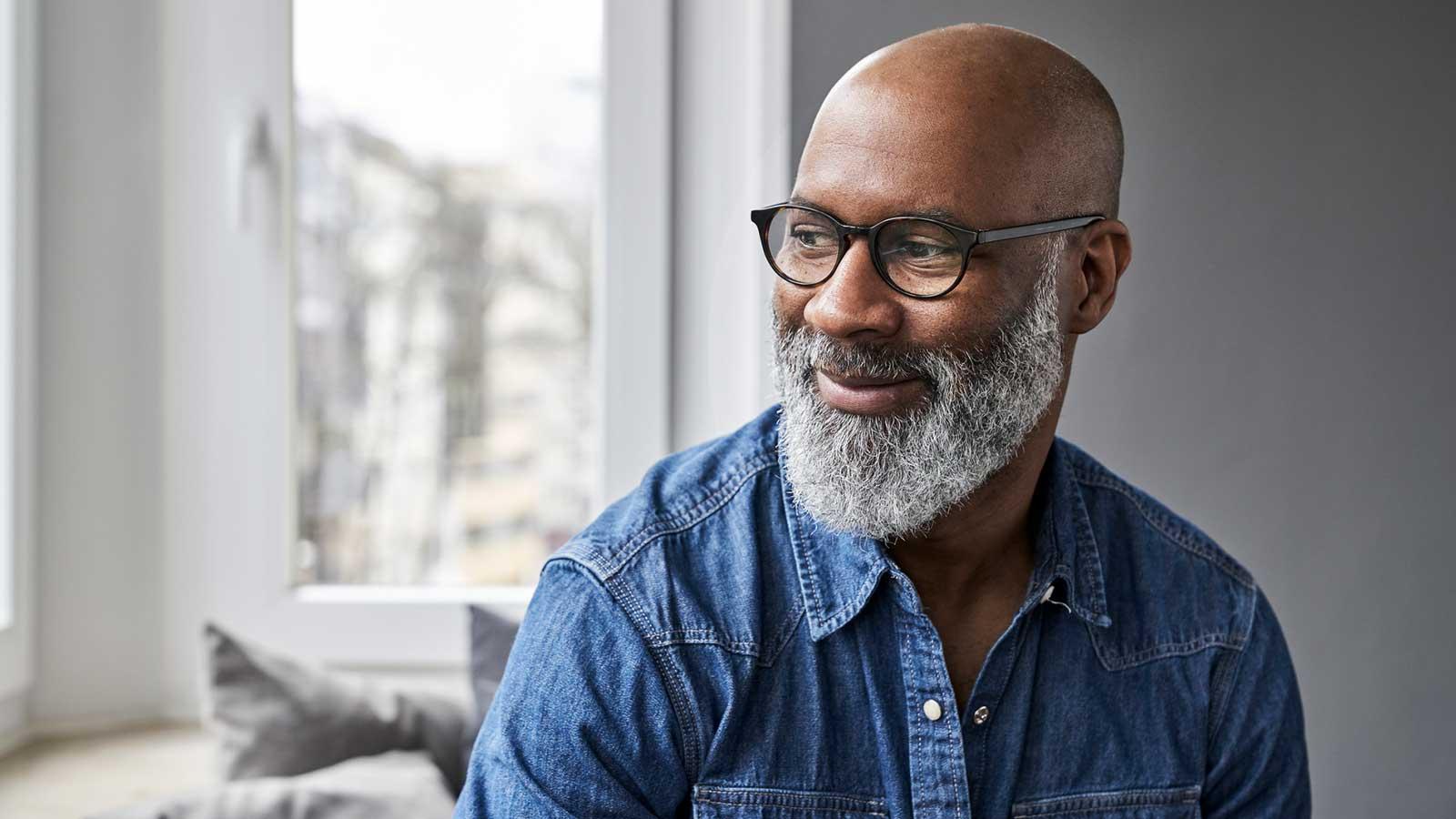 A bearded man wearing glasses relaxing on a couch