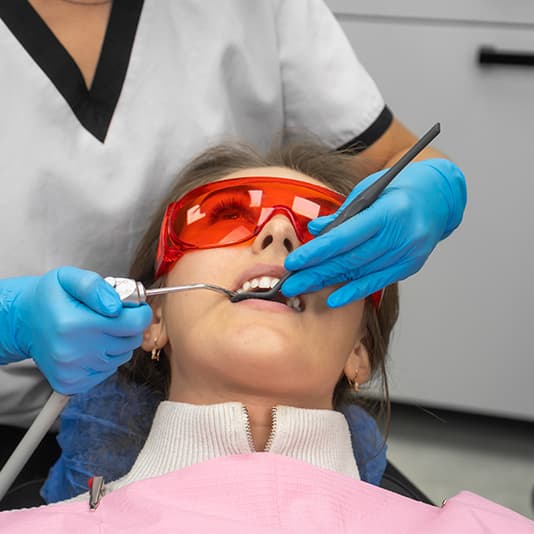 A woman sat in dental chair having teeth looked at