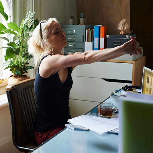 Woman stretching her arms at home desk