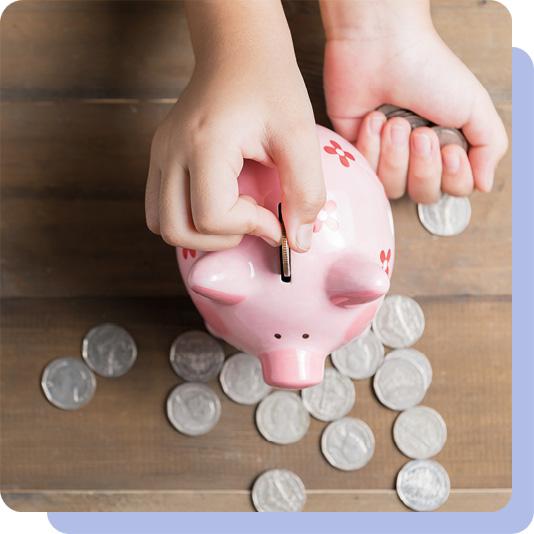 A hand putting silver coins into a piggy bank