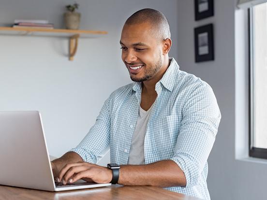 Smiling man sitting by a lap working from home