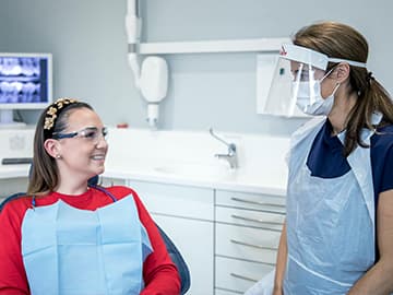 Dentist wearing PPE and talking to a patient