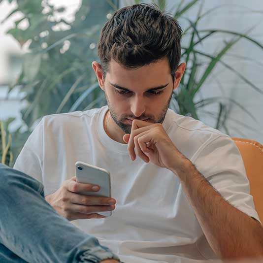 Man anxiously looking at mobile phone