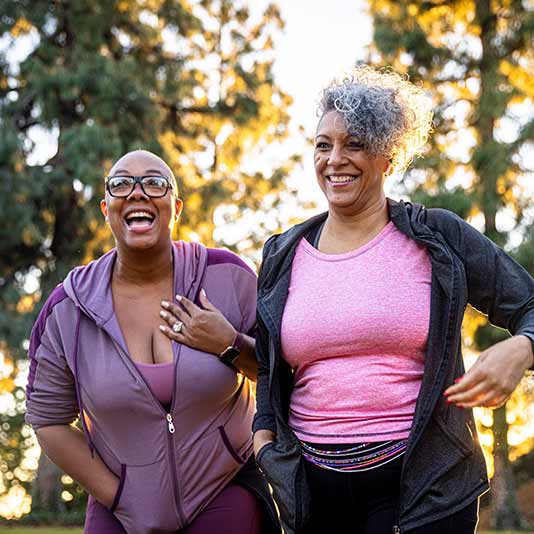 Two women smiling and laughing together while working out
