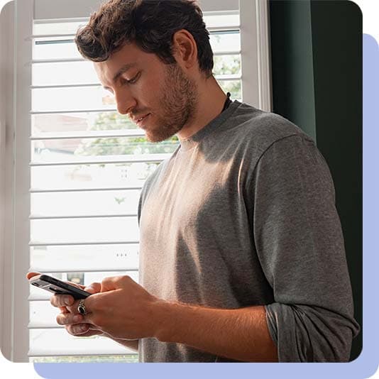 Man stood by window using his smart phone