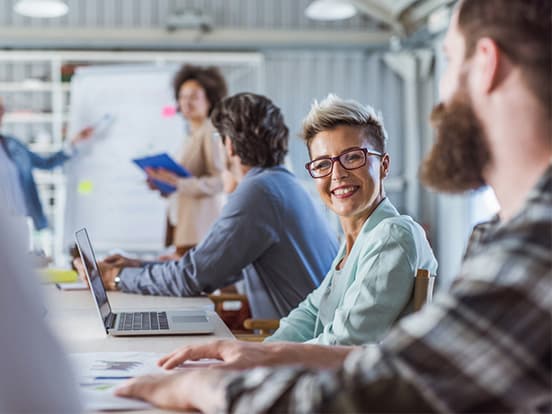 Woman in meeting room with colleagues, smiling