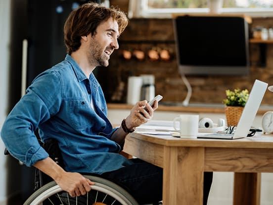 Man in wheelchair working from home by kitchen table
