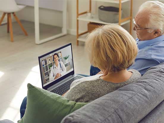 Couple on sofa having video call with GP