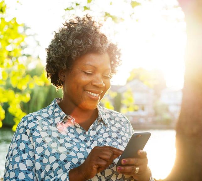 Senior woman using a smartphone outside in the sunshine