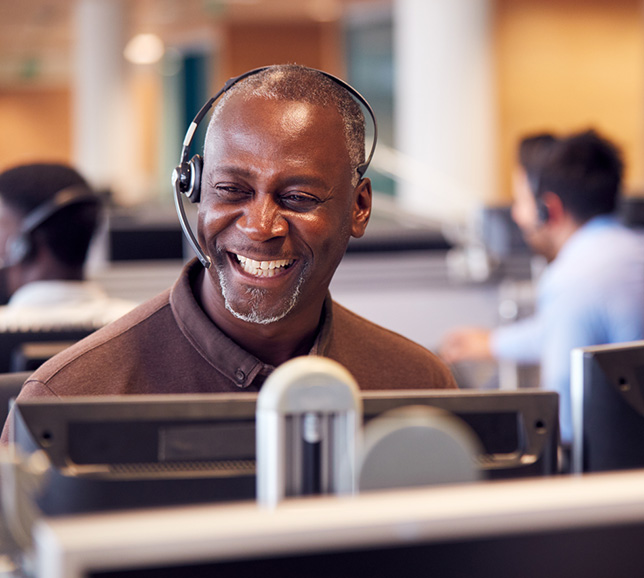 Man working in a call centre, wearing a headset, and smiling